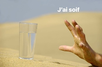 une main tendue vers un verre d'eau dans un désert